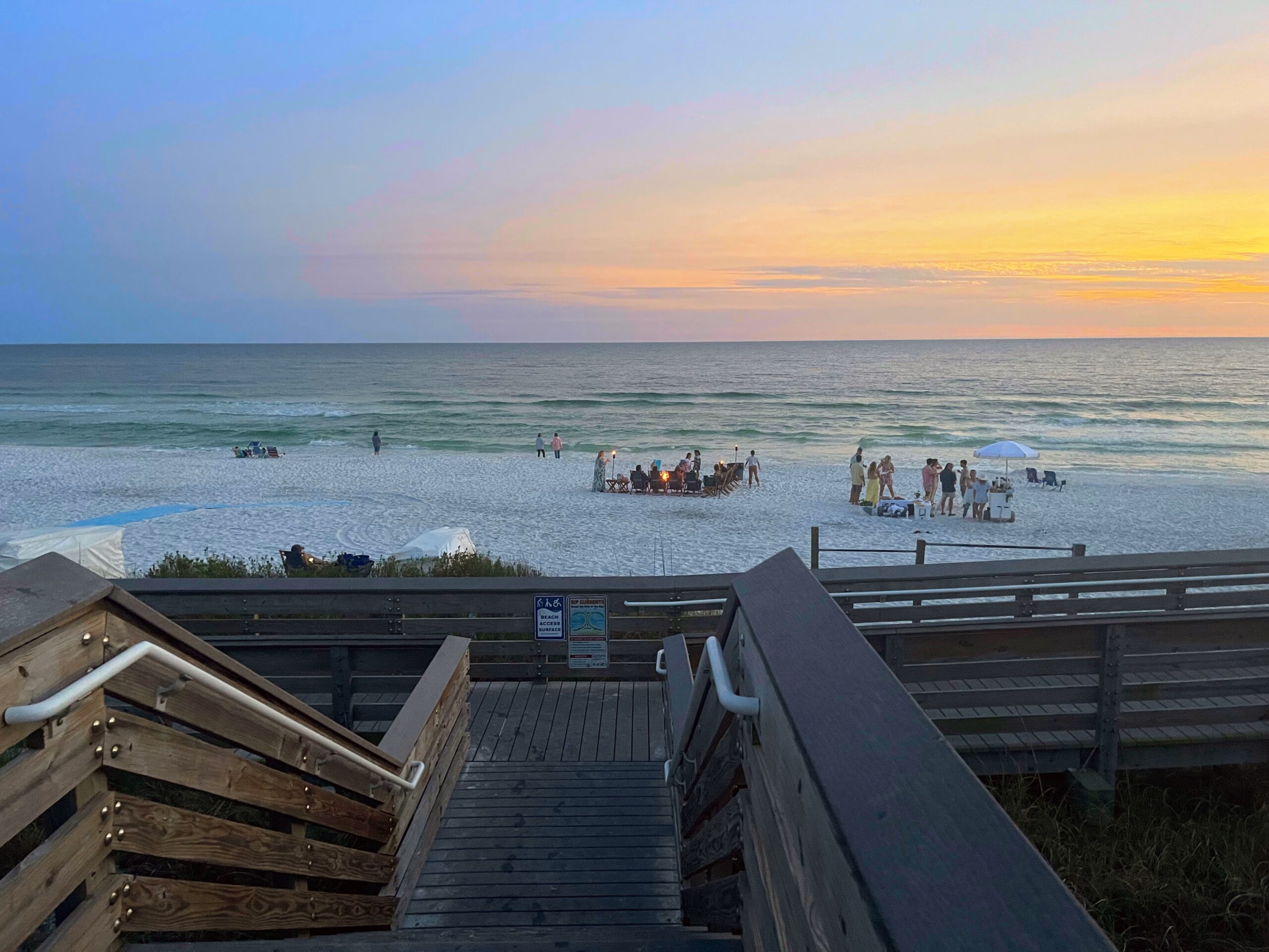 Sunset over the Gulf from the Ed Walline boardwalk, a family gathered on the sand