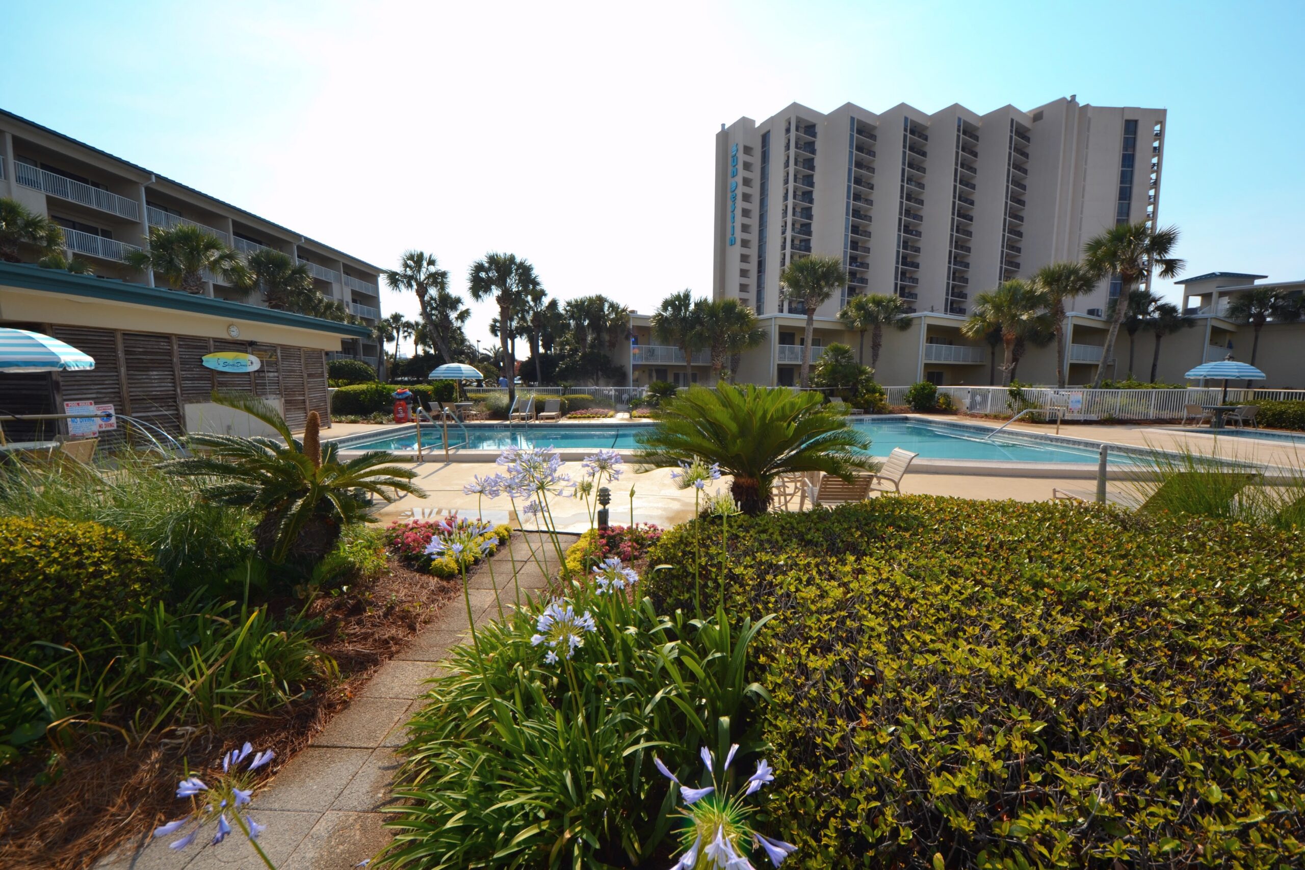 Destin Condo landscaped pool area sunny day mid day.