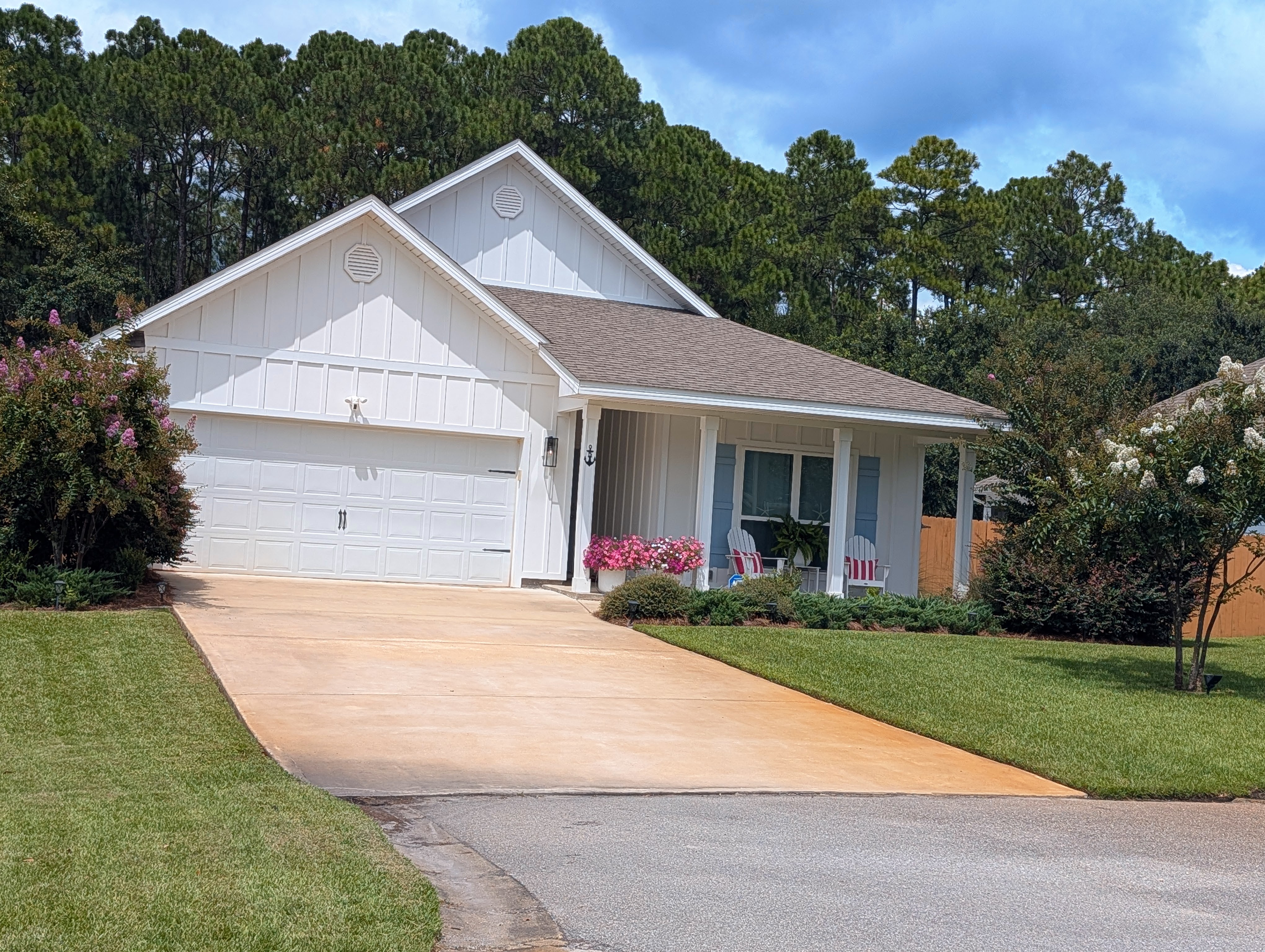 A white board-and-batten home in Paradise Cove with a two-car garage, covered front porch and pale blue shutters