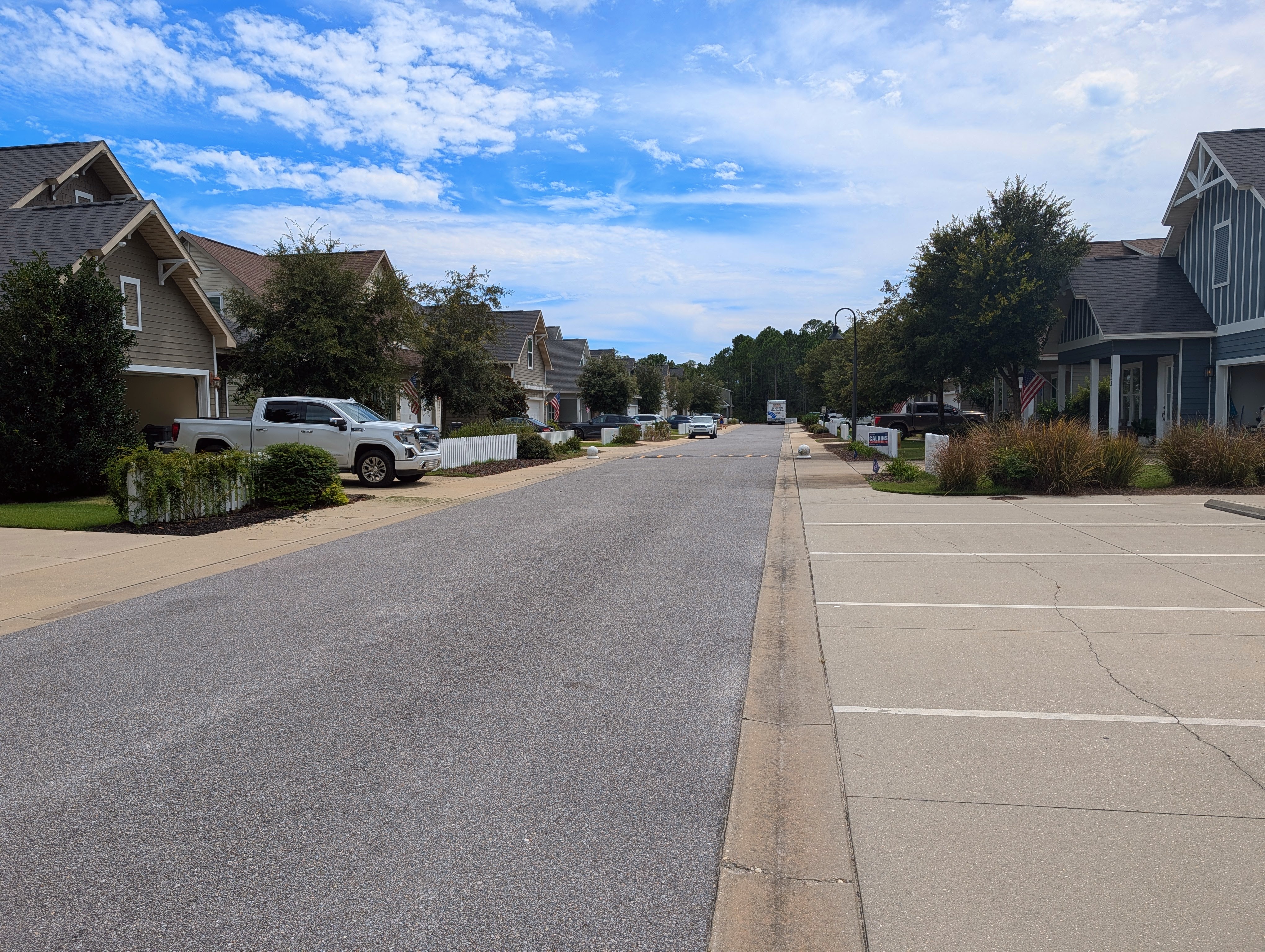 A residential street in Paradise Cove lined with two-story coastal-style homes, white picket fencing and porch flags